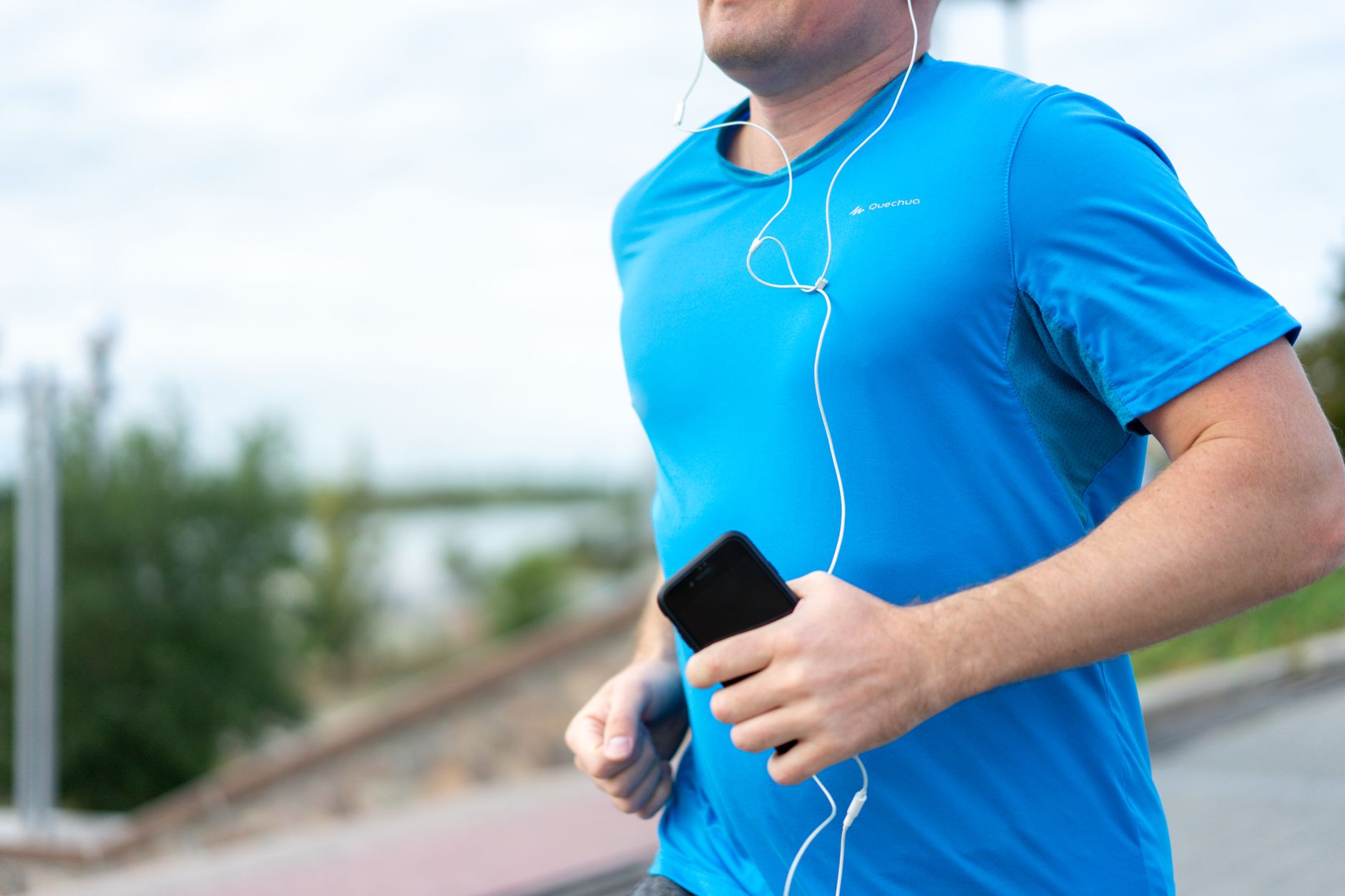 Man jogging outdoors while holding a smartphone in his hand