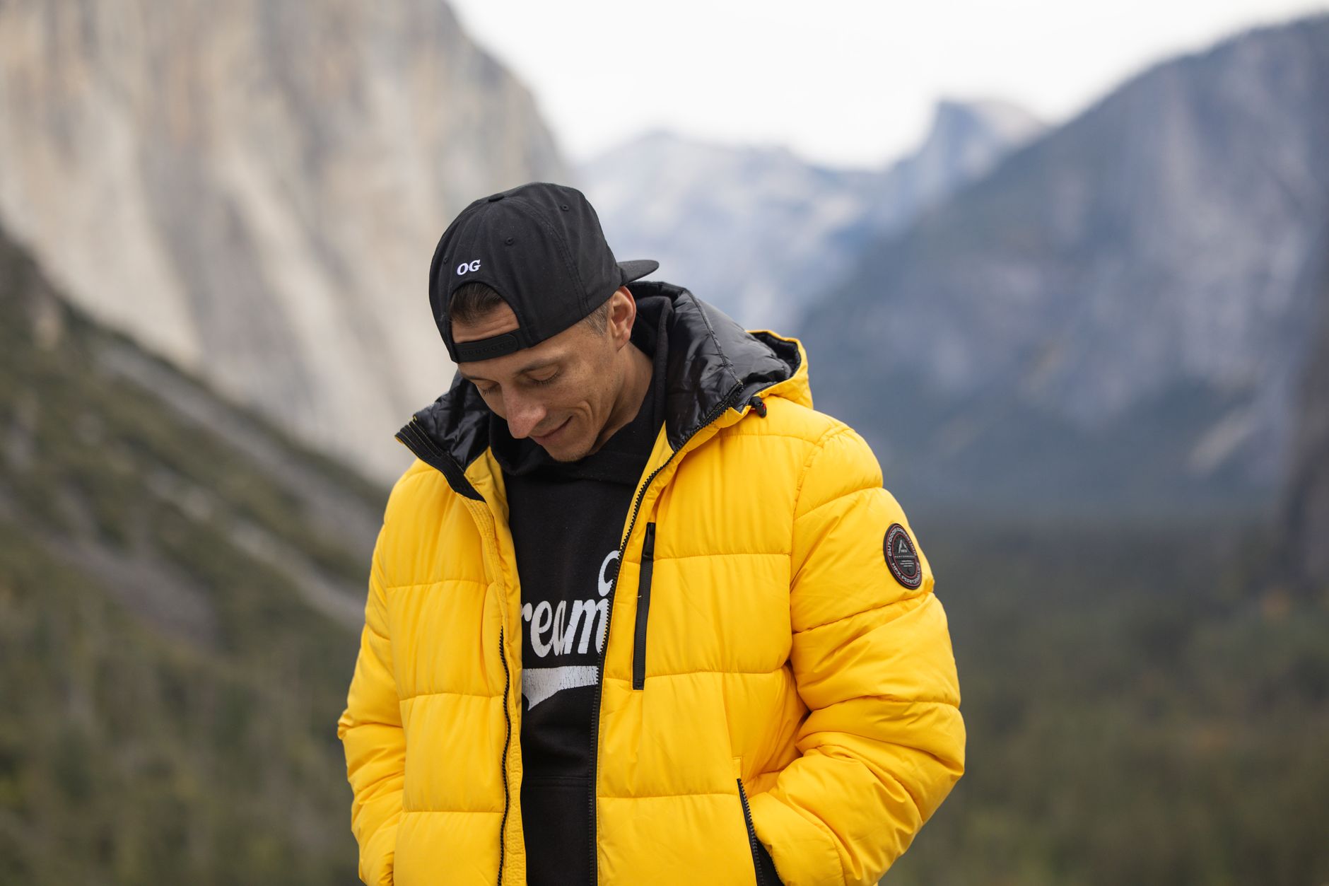 Person in an insulated yellow jacket standing in a mountainous landscape