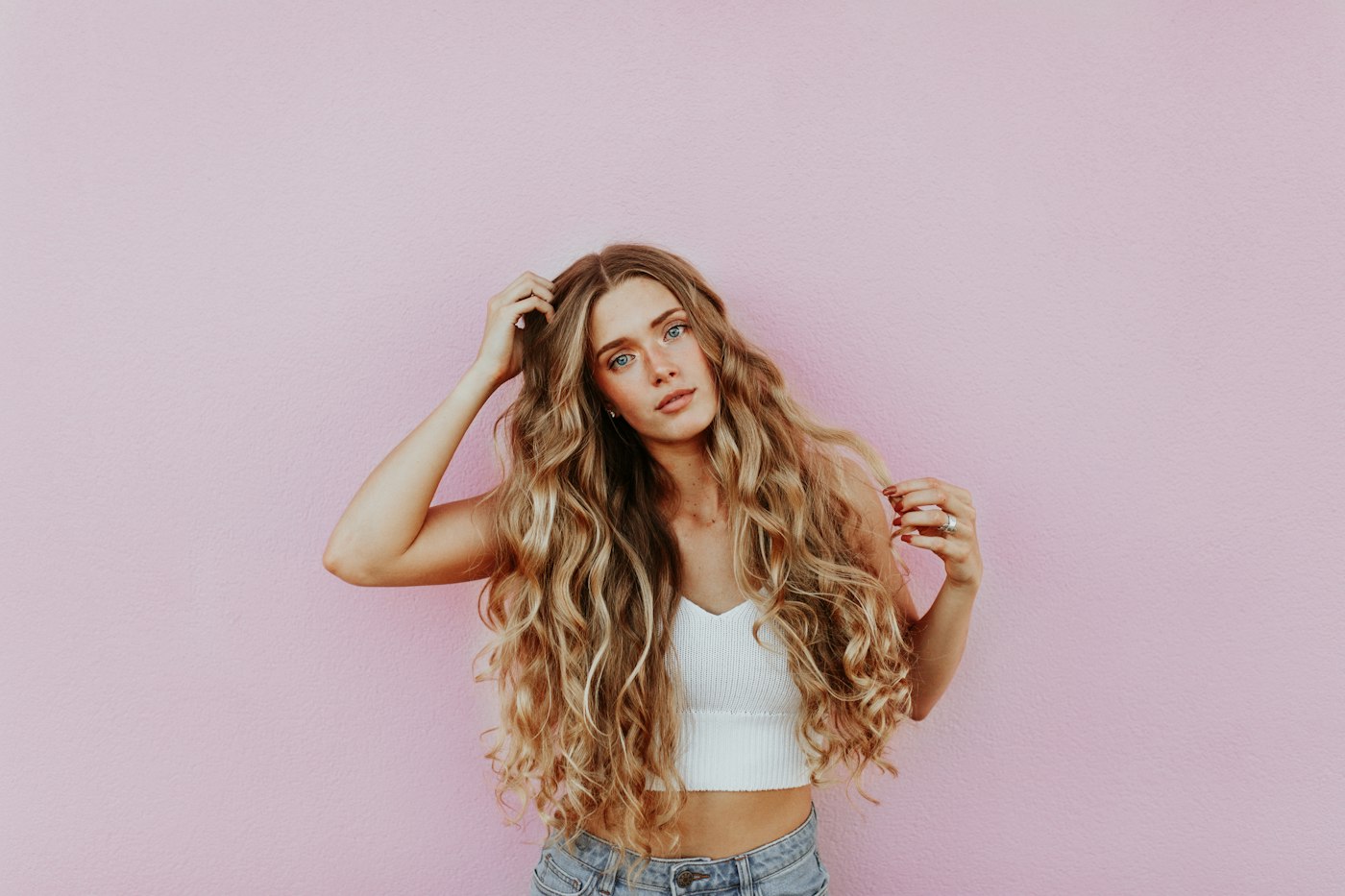 Woman with long wavy hair running her fingers through her hair at the scalp