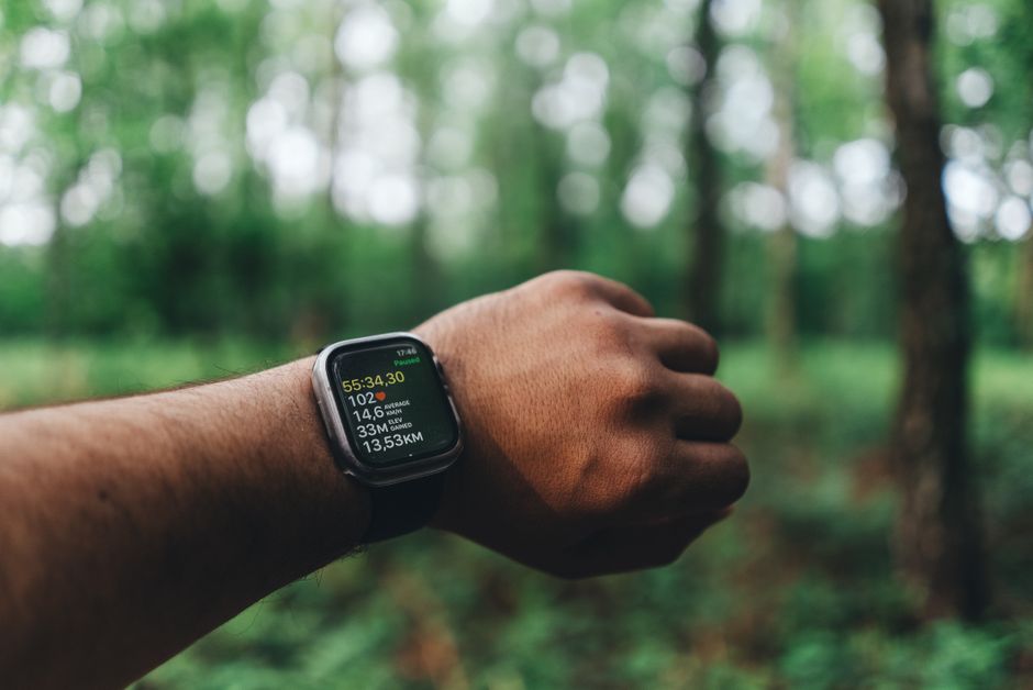 A runner's wrist showing fitness data on a smartwatch outdoors