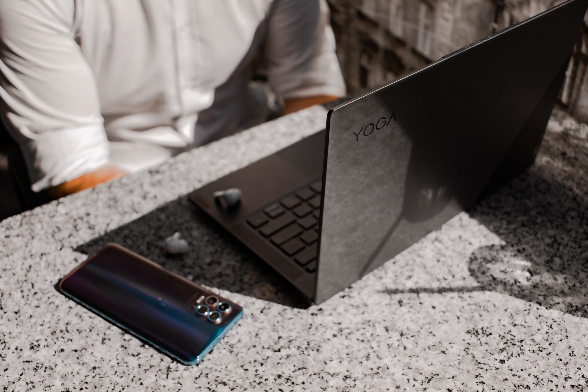 Laptop beside a smartphone and Bluetooth headset on a table