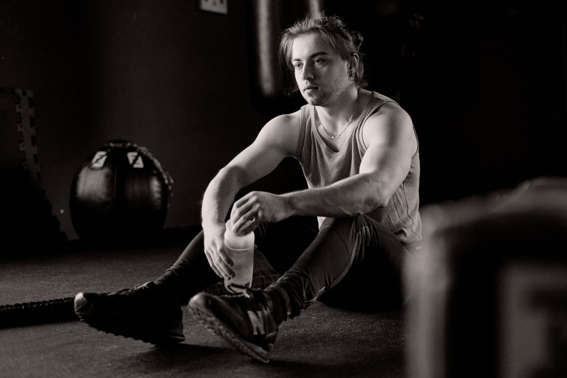 Man sitting on the floor resting with a water bottle after a workout