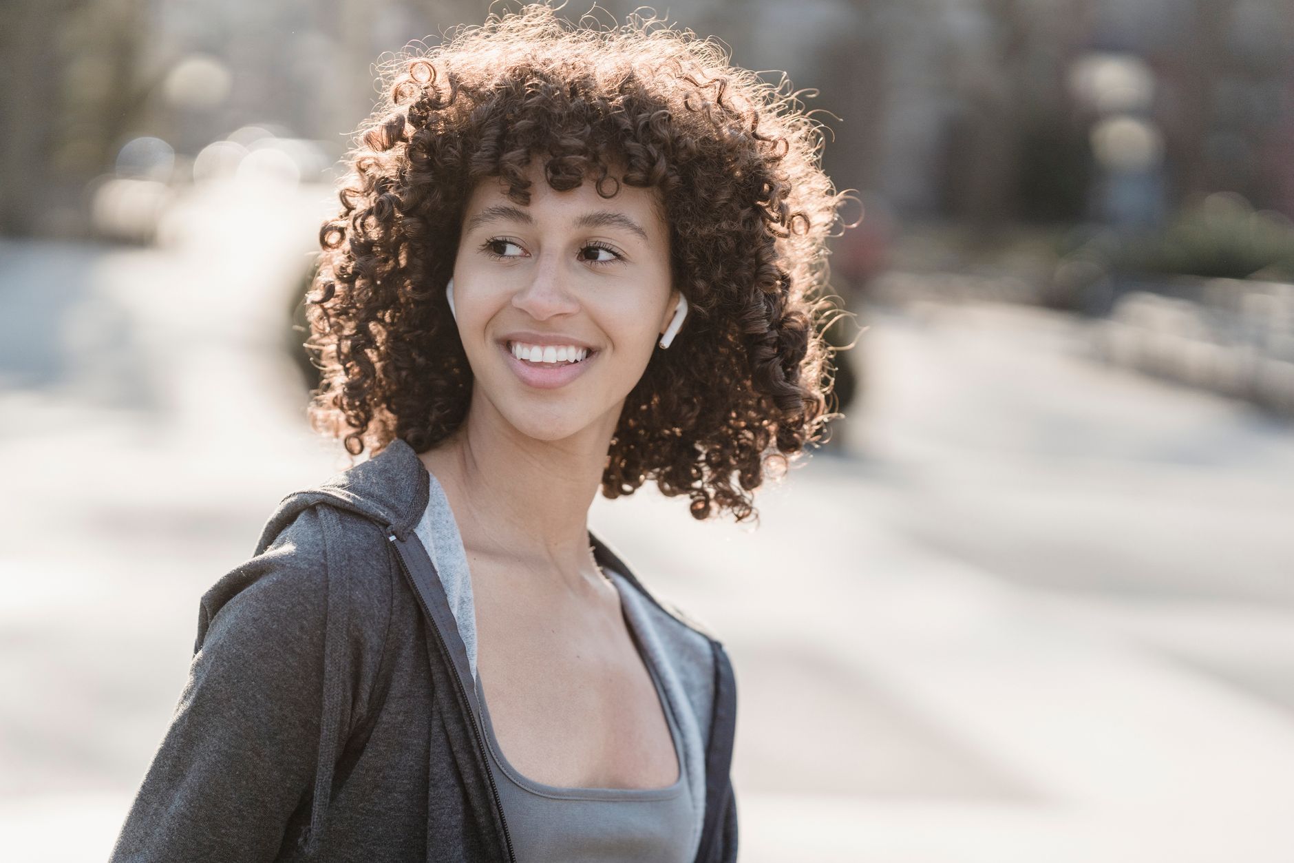 Woman smiling while wearing wireless earbuds outdoors