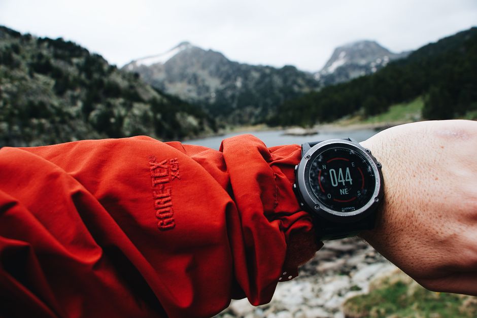A person checking a digital running watch outdoors in the mountains